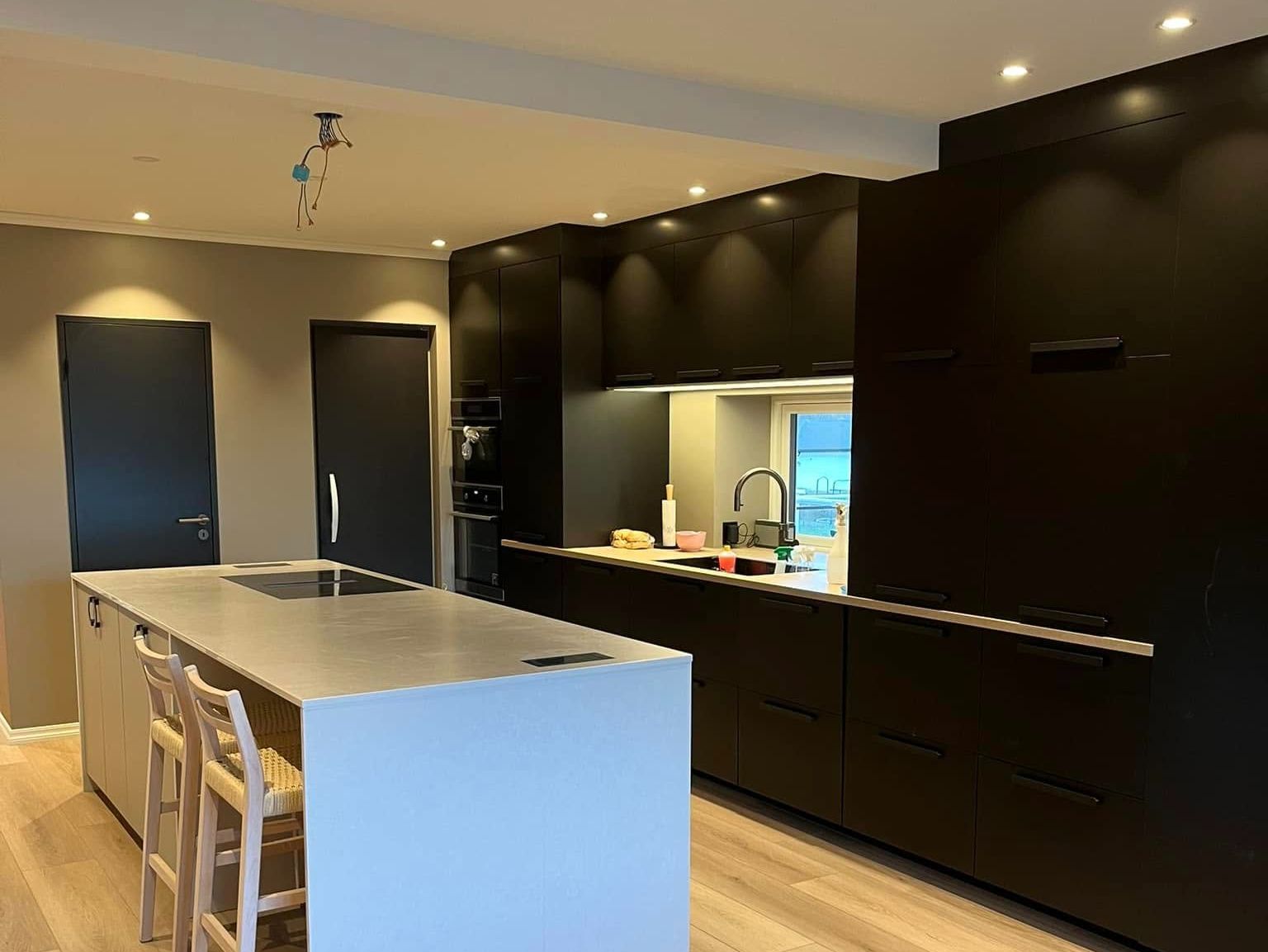 Moderne kjøkken med kjøkkenøy integrerte hvitevarer.